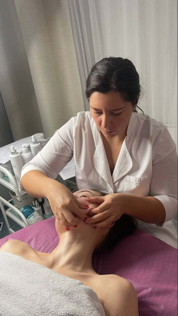 Person receiving a facial massage in a clinical setting.